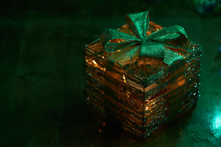 Close up of holiday golden gift box, electric blue garlands, fir branch and Christmas tree...