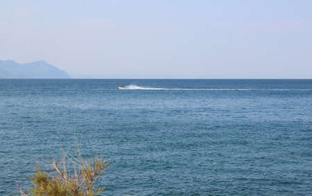 Seascape with mountains and people on a jet ski in the distance. Ocean backgroundの写真素材