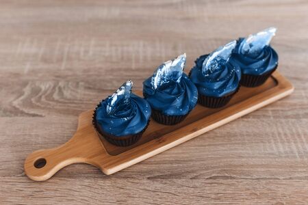Color of the year 2020. blue cupcakes with transparent caramel in the form of decoration stand on...