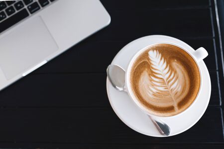 Cup of latte waiting for a working day on a wooden tableの写真素材