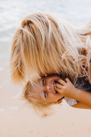 Happy mom on vacation hugs and kisses her laughing son in Asiaの写真素材