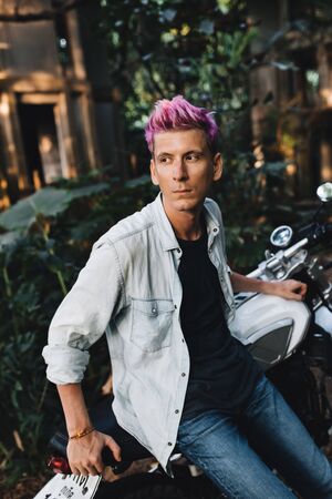 Serious guy on a bike in the jungle with colored hair