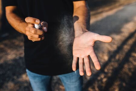 A man puffs a sanitizer on his hands on the streetの写真素材