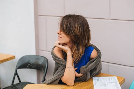 A girl sits on a summer terrace of a cafe waiting for her order