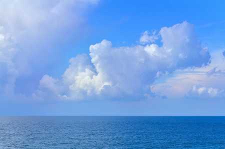 A puffy white, cloudy sky over the sea during a bright day.の写真素材