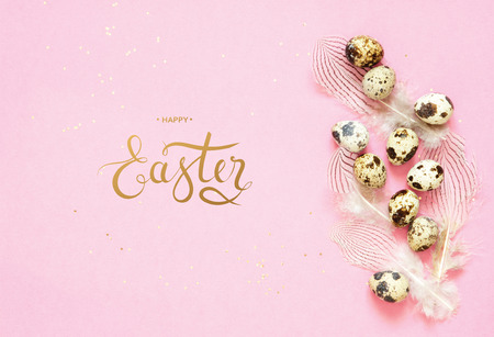Inscription Happy Easter. Easter composition with easter eggs and feathers on pink background.の写真素材