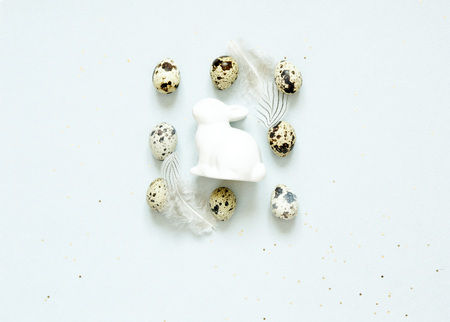 Easter composition with easter eggs, rabbit and feathers on blue background, space for text - Imageの写真素材