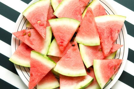 Fresh red watermelon slice in plate on striped background. Summer concept. Top view, Flat lay. -...