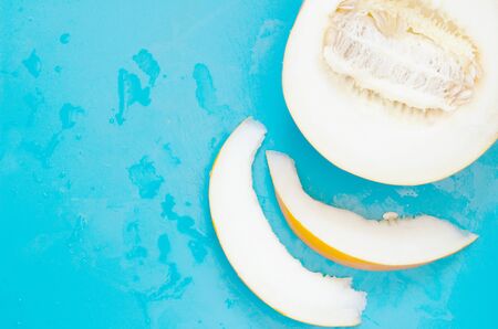 Yellow honeydew melon half with seeds and slices on blue background. - Imageの写真素材
