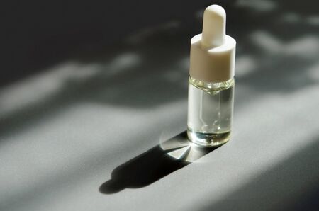 Cosmetic or medical glass bottle with pipette. Skin care concept. Natural hard light, deep shadows....