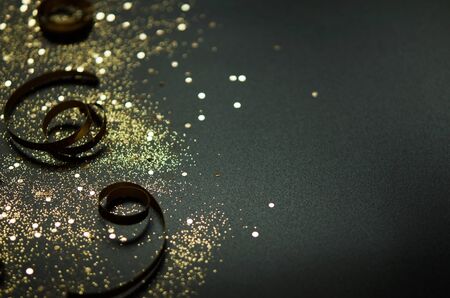 Golden sparkles and ribbons on black background. Festive concept. - Image