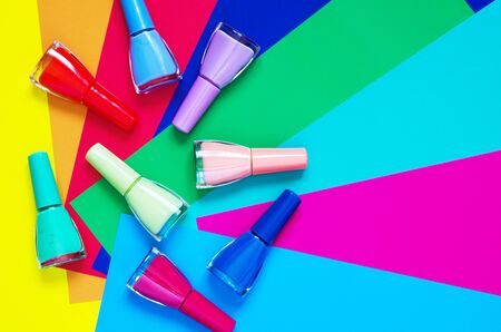 Colorful nails polish bottles on multi colored paper. The concept of fashion and beauty industry.の写真素材