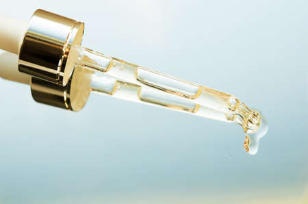 Liquid drop from cosmetic pipette close up, on mirror with reflection. Skin care concept. - Imageの写真素材