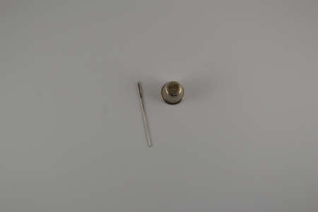 Sewing needle and thimble on white desk surface. Place for textの写真素材