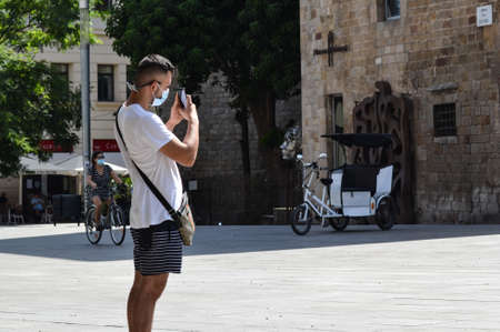 Barcelona, Spain, August 9, 2020: Tourists taking pictures and wearing protective medical masks to prevent virus Covid-19 in Barcelona, Spain, Europe. Tourist spots in the covid eraのeditorial素材