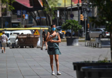 Barcelona, Spain, August 19, 2020: Young girl taking pictures on her phone and wearing protective medical masks to prevent virus Covid-19 in Barcelona, Spain, Europe.のeditorial素材