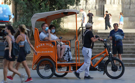 Barcelona, Spain, August 24, 2020: Caucasian tourists on a tuktuk wearing protective covid-19 face mask. Touristy spots in the covid eraのeditorial素材