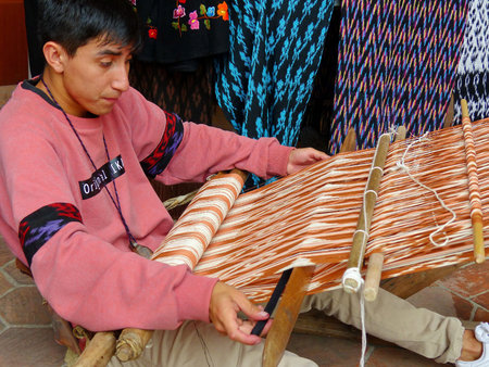 Cuenca, Ecuador - March 8, 2019: Ecuadorian man is weaving scarf or Macana by hand with cotton...