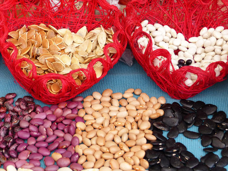 Collection set of multicolored beans and pumpkin seeds in wicker baskets on display at local farmer...