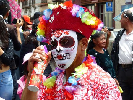 Cuenca, Ecuador - February 22, 2020: Parade during Carnival at historical center of city. Man in carnival mask and costume spraying foam which is traditional fun in Ecuadorのeditorial素材