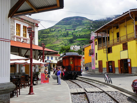 Alausi, Ecuador - February 18, 2015: Tourist railway from Alausi to  Nariz del Diablo or Devil's Nose. Railroad car parked in front of colorful buildings and train stationのeditorial素材