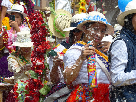 Cuenca, Ecuador - February 22, 2020: Carnival parade in Cuenca city. Woman in traditional costume for Azuay province spraying foam at participants which is tradition for this annual party in Ecuadorのeditorial素材