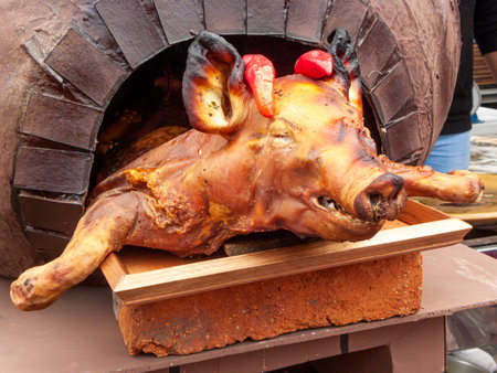 Whole roasted pig (chancho) is on decorative oven and ready for sale at the open market in Cuenca....