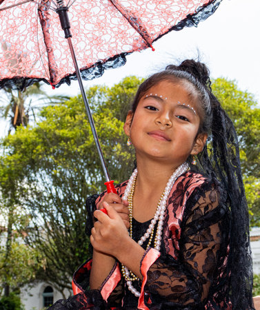 Cuenca, Ecuador - December 24, 2021: Christmas parade Paseo del Nino Viajero (traveling child), UNESCO cultural heritage. Beautiful girl in flamenco dress with umbrella smiles to pのeditorial素材