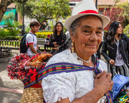 Cuenca, Ecuador - January 14,2023: Celebration 'Pase del NiÃ±o Viajero' (Traveling Child) in Cuenca city. Senior woman dress traditional for Azuay province carries basket with grillのeditorial素材
