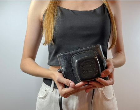 a young girl holds a retro film camera in her hands