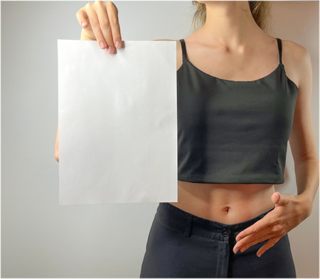 a young girl holds a white sheet of paper in her handsの写真素材
