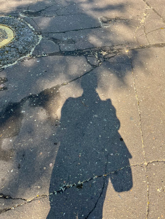 In summer, there is a shadow of a man on the old cracked asphaltの写真素材