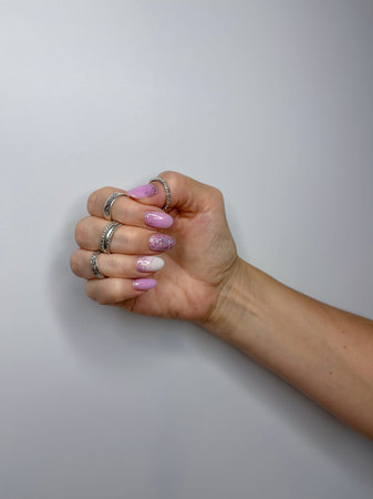 women's hands with a ring on their finger and nails painted with pink glitter varnish