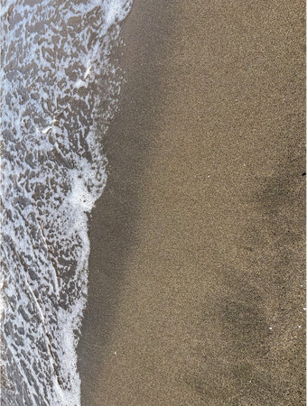 in summer in Georgia, a sea wave rolls over the black magnetic sand off the coast of Kobuleti