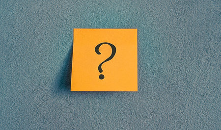 Hand-drawn question mark on an orange sticky noteの写真素材