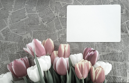 Tulips flowers bunch on Vintage newspaper background. Empty space for copy, text, lettering. Postcard, greeting card template.の写真素材
