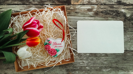 Ceramics heart inscription Love for ever. Tulips flowers bunch on dark barn wood planks background. Empty space for copy, text, lettering. Postcard, greeting card template.の写真素材