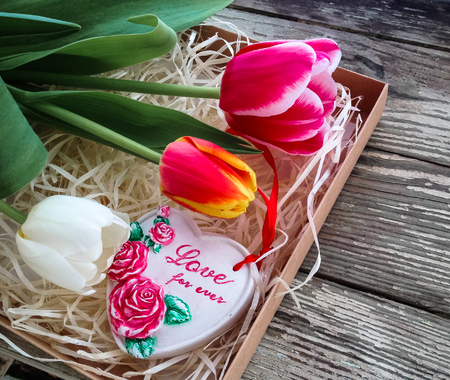 Ceramics heart inscription Love for ever. Tulips flowers bunch on dark barn wood planks background. Empty space for copy, text, lettering.の写真素材