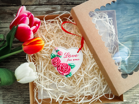 Ceramics heart inscription Love for ever. Tulips flowers bunch on dark barn wood planks background. Empty space for copy, text, lettering.の写真素材