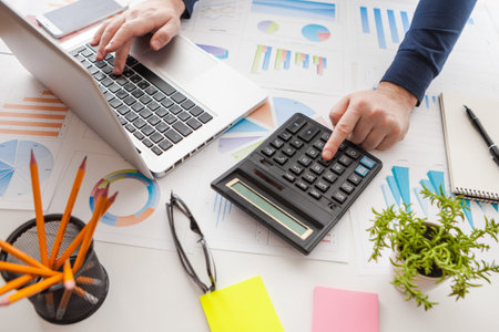 Businessman holding a pen is working with graph documents and sunset light background. Stock market...