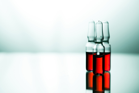 Ampoules with red liquid. On white background close up. Group of ampoules with a transparent medicine in medical laboratoryの写真素材