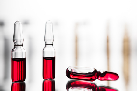 Ampoules with red liquid. On white background close up. Group of ampoules with a transparent medicine in medical laboratoryの写真素材