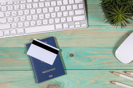 On the laptop desk foreign passport credit cards a notebook with a pen. Travel background, tourism and vacation planning, top view, copy space on white woodの写真素材