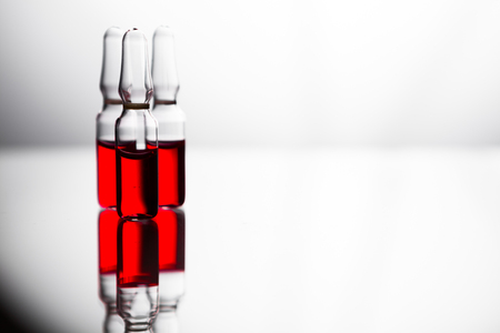 Ampoules with red liquid. On white background close up. Group of ampoules with a transparent medicine in medical laboratoryの写真素材