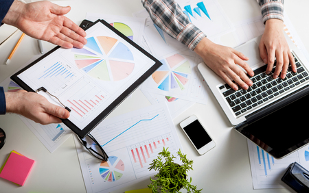 Business people discussing the charts and graphs showing the results of their successful teamwork.  Stock market chart and finger pointing on tablet in office.の写真素材