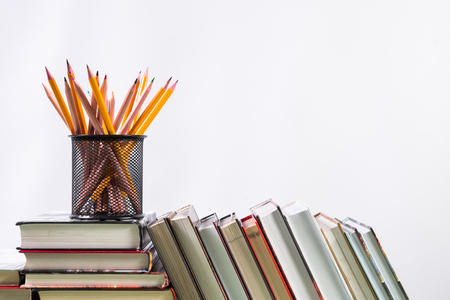 Set of pencils and pile of various books on wooden background. With copy space for your textの写真素材