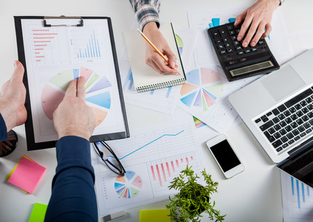 Business people discussing the charts and graphs showing the results of their successful teamwork.  Stock market chart and finger pointing on tablet in office.の写真素材