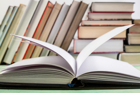 Open book and pile of various books on wooden background. With copy space for your textの写真素材