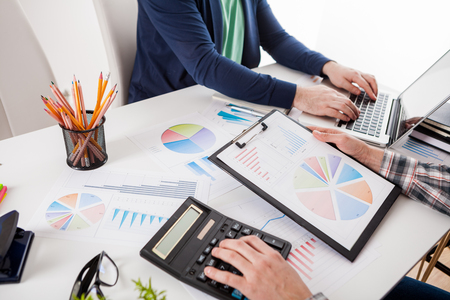 Business people discussing the charts and graphs showing the results of their successful teamwork.  Stock market chart and finger pointing on tablet in office.の写真素材
