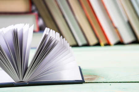 Open book and pile of various books on wooden background. With copy space for your textの写真素材